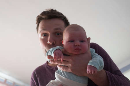 Young father and newborn baby girl spending time together