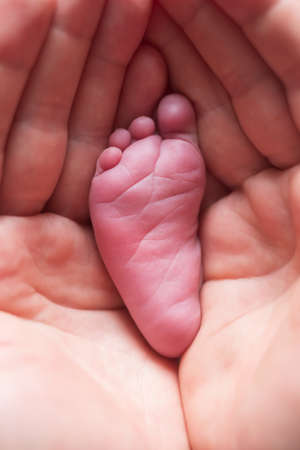 Parent holding little foot of his newborn baby.