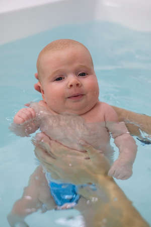 Caucasian 2 month baby exercising in swimming pool