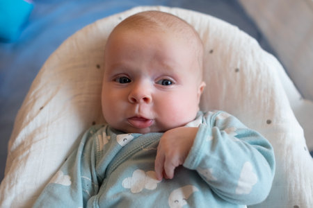 Baby girl looking at camera resting in bedの写真素材