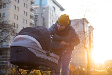 Happy young mother with pram during the walkの写真素材