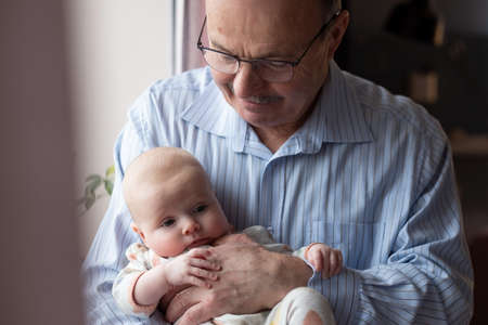 Grandfather holding a beautiful newborn baby girlの写真素材