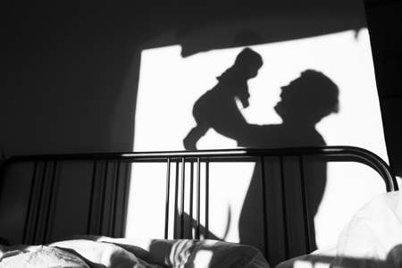 silhouette of a child and parent who are playing in the room in the morning.の写真素材