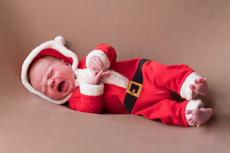Newborn girl dressed in santa claus costume looking at camera with confused face.の写真素材