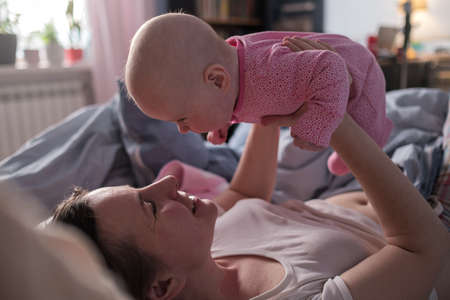 Happy loving caucasian mother spending time, playing with baby girl.