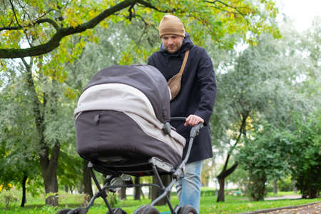 Happy young father with pram during the walk in natureの写真素材