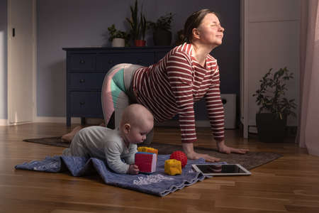 Mother with baby make yoga at home to be strong and healthy