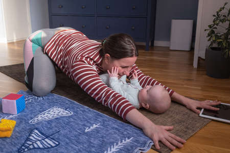 Mother with baby make yoga at home to be strong and healthyの写真素材