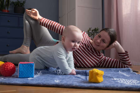 Caucasian mother with baby make yoga at home to be strong and healthy,の写真素材
