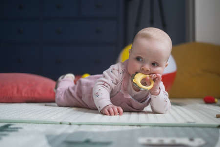 six months old caucasian baby on the floor with a toy