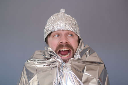 Young man in a cap of foil being afraid and stressed.の写真素材