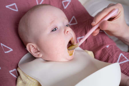 Feeding a little caucasian baby for first time.の写真素材