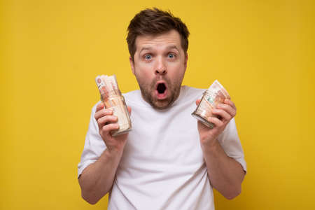 Caucasian man holding a jar full of money.