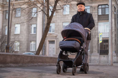 Grandfather walking with a baby stroller on snowy winter dayの写真素材