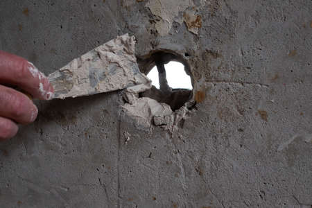 Fixing hole on the wall, spreading plaster using trowelの写真素材