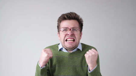 Man in green sweater and big glasses with nervous crisis. I will kill you.の写真素材