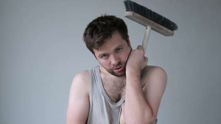 Tired young man with mop on white backgroundの写真素材