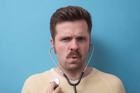 Caucasian patient with mustache listening to his heart beating. Self control. Studio shotの写真素材