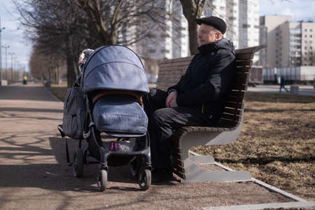 Grandfather walking with a baby stroller on spring day
