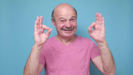 Middle age man smiling positive doing ok sign approving choice. positive facial human emotion.