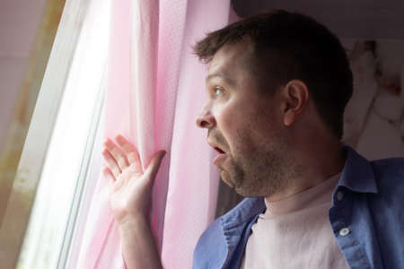 Anxious caucaisian man feel nervous pessimistic look at window wait for someone has mental health...