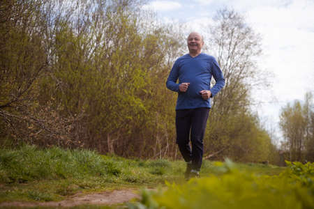 Active senior man is jogging in park. Healthy retirement lifestyle.