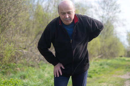 Senior man with pain on heart walking alone outdoor