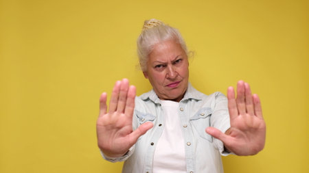 Elderly European woman showing a stop gesture with her handsの写真素材