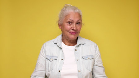 An elderly European woman in glasses confidently looks into the camera, smiling. studio shot