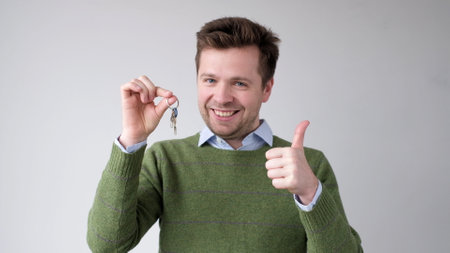 A European young man shows the keys to his new apartment. He is happy to have bought his own home. studio shotの写真素材