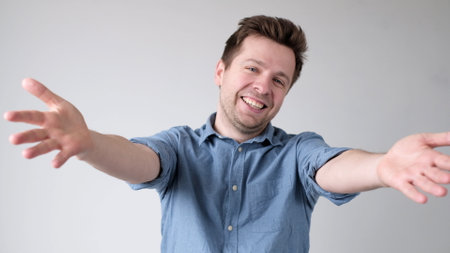 European young man is reaching out his hands forward to embrace the interlocutor, greeting him. studio shotの写真素材