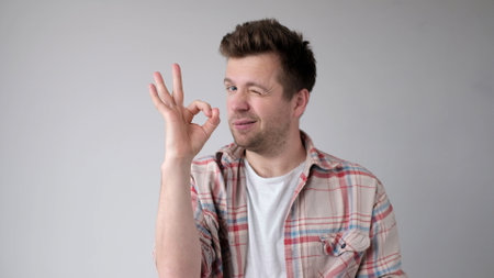 The European young man shows the okay gesture, saying everything is done excellently. studio shotの写真素材