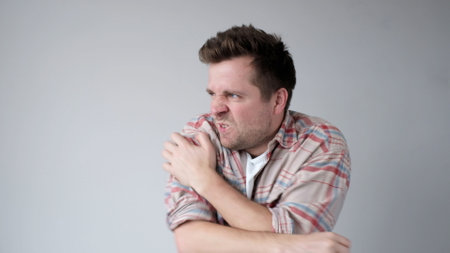 The European young man nervously scratches his hands. He has an allergy, and the itching bothers him. studio shotの写真素材