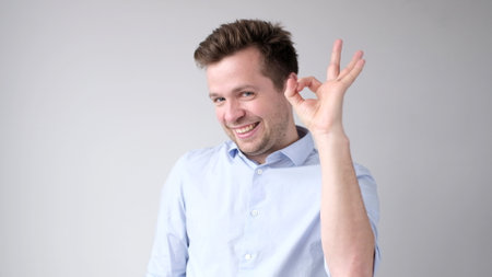 The European young man shows the okay gesture, saying everything is done excellently. studio shotの写真素材