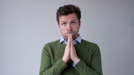 European young man asks for help, holds palms together. studio shotの写真素材