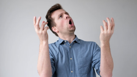 European young man pretends to sing a song loudly. studio shotの写真素材