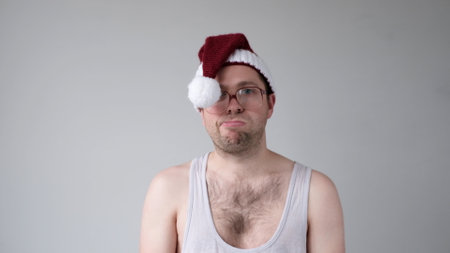 The sad and sorrowful European young man in a New Year's hat looks gloomily into the camera. Disappointments in the New Year celebration. studio shotの写真素材