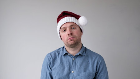 The sad and sorrowful European young man in a New Year's hat looks gloomily into the camera. Disappointments in the New Year celebration. studio shotの写真素材