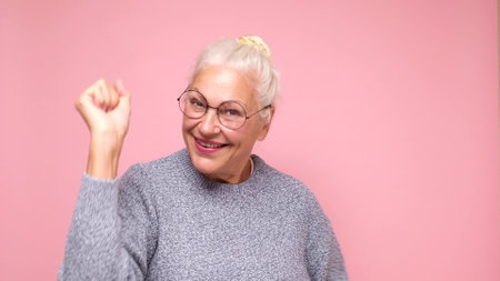 An elderly European woman in glasses confidently looks into the camera, smiling