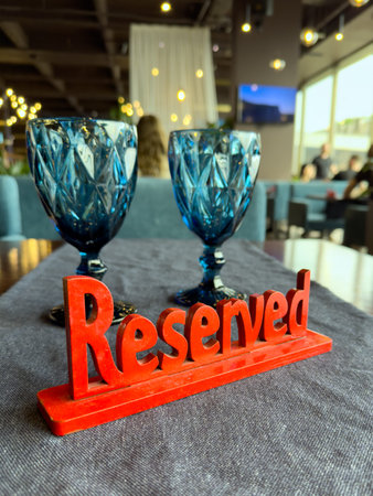 a red wooden sign reserved on a table against the background of two transparent glasses