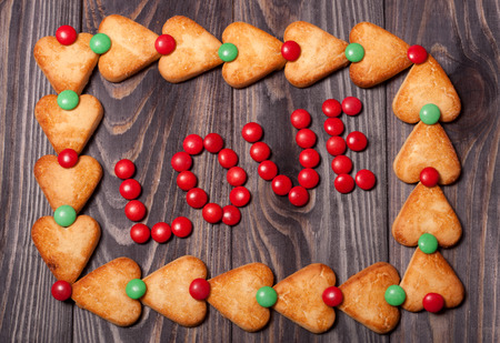 word love from candies on wooden background in frame of cookiesの写真素材