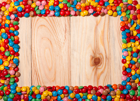 Frame of colorful candy on wood background with space for your text.の写真素材