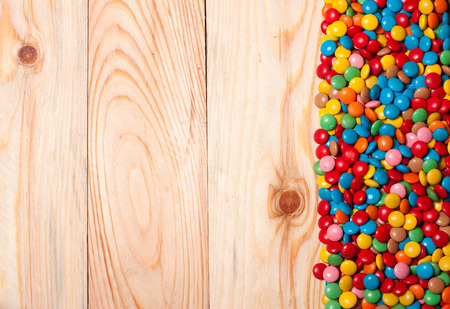 Frame of colorful candy on wood background with space for your text.の写真素材