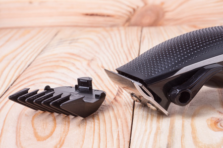 hair trimmer  with attachment on a light wooden background closeup.