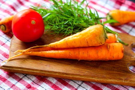 still life of carrot on the cutting board with tomato.の写真素材