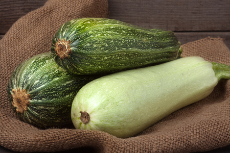 green zucchini and courgette on sackcloth and wooden background.の写真素材