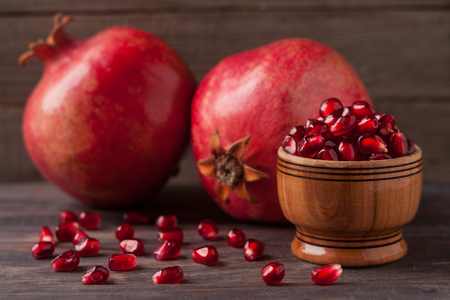 two pomegranate and grains in the bowl on the old wooden background.の写真素材