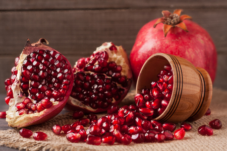 pomegranate and grains in the bowl on the old wooden board with sackcloth.の写真素材