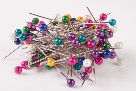pile of of multi-colored sewing pins on a white background.