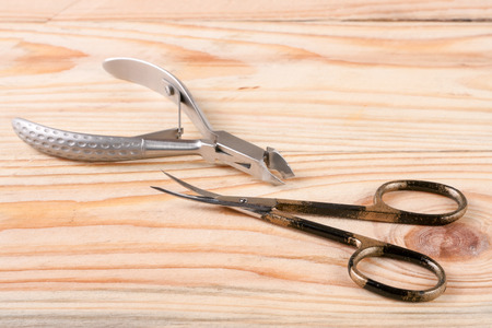 nail scissors and clippers to remove the cuticle care products on a light wooden background